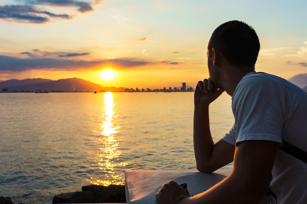 Man looking pensively out to sunset - time management.