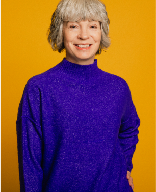 Smiling woman with short hair and purple sweater with yellow background - staffing support.