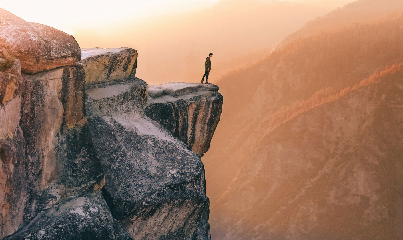 Person at the edge of a high cliff looking down into a canyon - internal communications jobs.